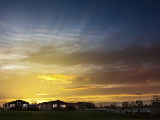 Sunset over the luxury holiday lodges at Arrow Bank Country Holiday Park